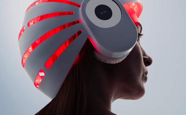 Woman using a red light therapy helmet for simulating hair growth naturally