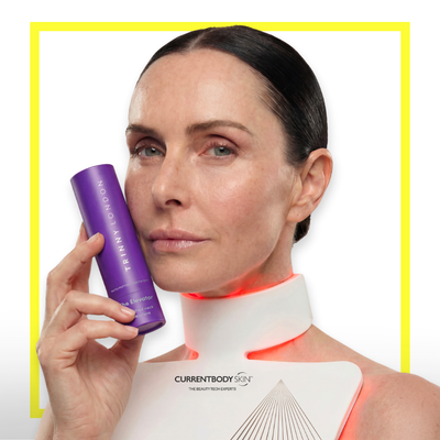 Woman wearing the CurrentBody LED Neck & Decolletage Mask and holding Trinny London The Elevator